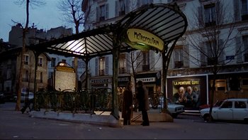 Movie still from “The Tenant” (1976), directed by Roman Polanski – Two people are standing at a bus stop in the evening; Wide shot, Low angle