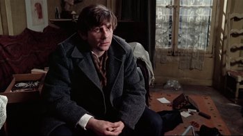 Movie still from “The Tenant” (1976), directed by Roman Polanski – A man sitting on the ground in a room; Medium shot, High angle