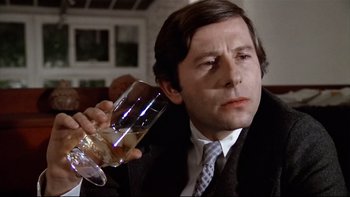 Movie still from “The Tenant” (1976), directed by Roman Polanski – A man in a suit and tie holding a wine glass; Close Up shot, Low angle