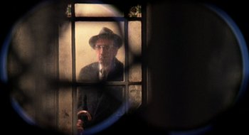 Movie still from “The Tenant” (1976), directed by Roman Polanski – An old man wearing a hat looking out of a window; Medium shot, Low angle