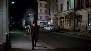 Movie still from “The Tenant” (1976), directed by Roman Polanski – A man walking down a street at night; Wide shot, High angle