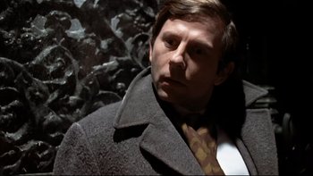 Movie still from “The Tenant” (1976), directed by Roman Polanski – A person wearing a suit and tie; Close Up shot, Over the shoulder angle