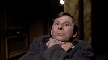 Movie still from “The Tenant” (1976), directed by Roman Polanski – A man sitting down with his hands on his chin; Close Up shot, Low angle