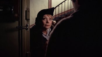 Movie still from “The Tenant” (1976), directed by Roman Polanski – A woman wearing a hat looking at a man; Close Up shot, Over the shoulder angle