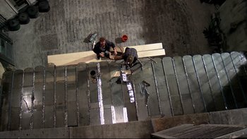 Movie still from “The Tenant” (1976), directed by Roman Polanski – Two men working together on a wooden beam; Wide shot, Overhead angle