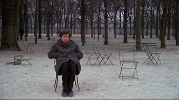 Movie still from “The Tenant” (1976), directed by Roman Polanski – A person sitting on a chair in a park; Wide shot, High angle