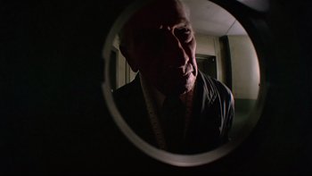 Movie still from “The Tenant” (1976), directed by Roman Polanski – An older man looking into a mirror with a measuring tape around his neck; Close Up shot, Low angle
