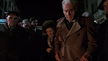 Movie still from “The Tenant” (1976), directed by Roman Polanski – An older man in a brown coat and a woman in a brown coat; Medium shot, High angle