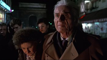 Movie still from “The Tenant” (1976), directed by Roman Polanski – An older man in a trench coat standing next to a woman; Close Up shot, Low angle