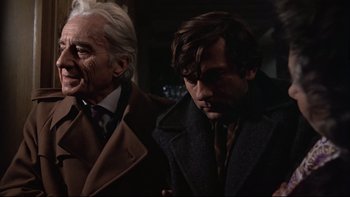 Movie still from “The Tenant” (1976), directed by Roman Polanski – A man in a suit and tie standing next to another man in a suit and tie; Close Up shot, Over the shoulder angle