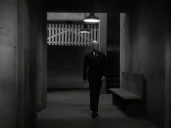 Movie still from “The Thin Man” (1934), directed by W.S. Van Dyke – A black and white photo of a man in a suit walking down a hall way; Wide shot, Low angle