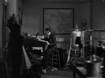 Movie still from “The Thin Man” (1934), directed by W.S. Van Dyke – A black and white photo of a man sitting in a room; Wide shot, High angle