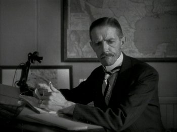 Movie still from “The Thin Man” (1934), directed by W.S. Van Dyke – A black and white photo of a man in a suit writing; Medium shot, High angle