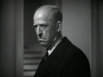 Movie still from “The Thin Man” (1934), directed by W.S. Van Dyke – An older man wearing a suit and tie in front of a staircase; Close Up shot, Low angle