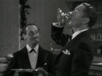 Movie still from “The Thin Man” (1934), directed by W.S. Van Dyke – Two men in tuxedos are drinking from a wine glass; Medium shot, Low angle