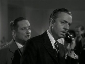 Movie still from “The Thin Man” (1934), directed by W.S. Van Dyke – A man talking on a phone next to another man; Close Up shot, Low angle