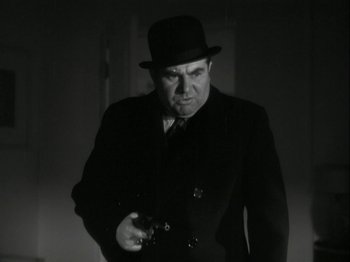 Movie still from “The Thin Man” (1934), directed by W.S. Van Dyke – A man in a suit and a hat holding a gun; Close Up shot, Low angle