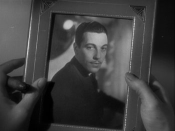Movie still from “The Thin Man” (1934), directed by W.S. Van Dyke – A person holding a picture of a man in a suit; Close Up shot, High angle