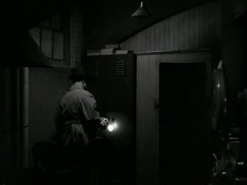 Movie still from “The Thin Man” (1934), directed by W.S. Van Dyke – A man standing in front of an open door in a dark room; Wide shot, High angle