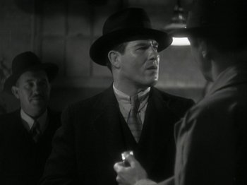 Movie still from “The Thin Man” (1934), directed by W.S. Van Dyke – A black and white photo of a man in a suit and a hat; Close Up shot, Over the shoulder angle