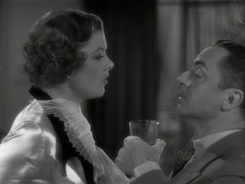 Movie still from “The Thin Man” (1934), directed by W.S. Van Dyke – A man and a woman holding a wine glass in front of each other; Close Up shot, High angle