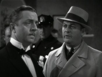 Movie still from “The Thin Man” (1934), directed by W.S. Van Dyke – Two men in suits and a hat are standing together; Close Up shot, High angle