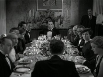 Movie still from “The Thin Man” (1934), directed by W.S. Van Dyke – A group of people sitting around a table with food on it; Wide shot, High angle