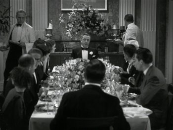 Movie still from “The Thin Man” (1934), directed by W.S. Van Dyke – A group of people sitting at a table with food on top of it; Wide shot, High angle