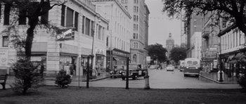 Movie still from “The Three Faces of Eve” (1957), directed by Nunnally Johnson – An old photo of a street with cars parked on the side of the road; Extreme Wide shot, Low angle
