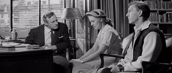 Movie still from “The Three Faces of Eve” (1957), directed by Nunnally Johnson – An old photo of a man and a woman sitting in a room; Medium shot, Low angle