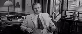 Movie still from “The Three Faces of Eve” (1957), directed by Nunnally Johnson – An old photo of a man in a suit and tie; Medium shot, Low angle