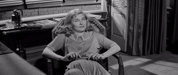 Movie still from “The Three Faces of Eve” (1957), directed by Nunnally Johnson – An old photo of a woman sitting in a chair; Medium shot, High angle