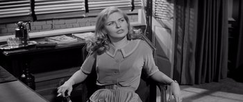 Movie still from “The Three Faces of Eve” (1957), directed by Nunnally Johnson – A black and white photo of a woman sitting in a chair; Medium shot, Over the shoulder angle