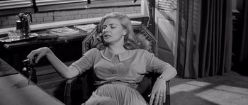 Movie still from “The Three Faces of Eve” (1957), directed by Nunnally Johnson – A woman sitting in a chair with her eyes closed; Medium shot, High angle