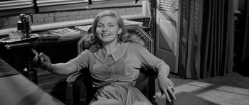 Movie still from “The Three Faces of Eve” (1957), directed by Nunnally Johnson – An old photo of a woman sitting in a chair smiling; Medium shot, Low angle