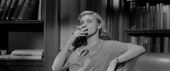 Movie still from “The Three Faces of Eve” (1957), directed by Nunnally Johnson – A woman smoking a cigarette while sitting on a chair; Medium shot, Low angle