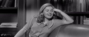 Movie still from “The Three Faces of Eve” (1957), directed by Nunnally Johnson – An old photo of a woman sitting in a chair smiling; Medium shot, High angle