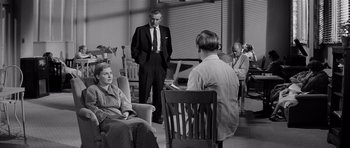 Movie still from “The Three Faces of Eve” (1957), directed by Nunnally Johnson – An old photo of a group of people sitting in a room; Wide shot, Over the shoulder angle
