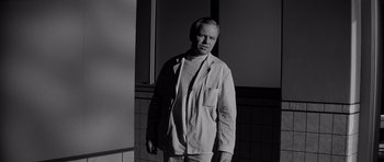 Movie still from “The Three Faces of Eve” (1957), directed by Nunnally Johnson – Black and white photograph of a man standing in front of tiled wall; Medium shot, Low angle