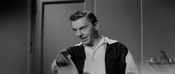 Movie still from “The Three Faces of Eve” (1957), directed by Nunnally Johnson – A black and white photo of a man holding a frisbee; Close Up shot, Over the shoulder angle