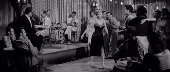 Movie still from “The Three Faces of Eve” (1957), directed by Nunnally Johnson – An old photo of a woman singing in front of a crowd; Wide shot, High angle