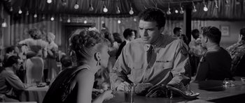 Movie still from “The Three Faces of Eve” (1957), directed by Nunnally Johnson – A man and a woman are talking at a bar; Medium shot, Over the shoulder angle