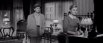 Movie still from “The Three Faces of Eve” (1957), directed by Nunnally Johnson – A man and a woman standing next to each other in a room; Medium shot, Over the shoulder angle