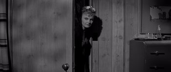 Movie still from “The Three Faces of Eve” (1957), directed by Nunnally Johnson – A black - and - white photo of a woman peeking through a door; Medium shot, Low angle