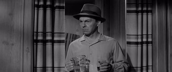 Movie still from “The Three Faces of Eve” (1957), directed by Nunnally Johnson – A black and white photo of a man in a hat holding glasses; Close Up shot, Over the shoulder angle