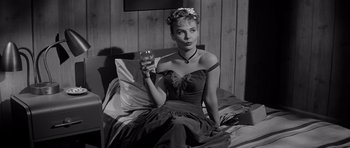 Movie still from “The Three Faces of Eve” (1957), directed by Nunnally Johnson – A black and white photo of a woman holding a glass of wine; Medium shot, Low angle