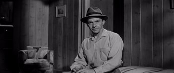 Movie still from “The Three Faces of Eve” (1957), directed by Nunnally Johnson – A man wearing a hat sitting on a chair; Medium shot, Low angle