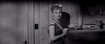 Movie still from “The Three Faces of Eve” (1957), directed by Nunnally Johnson – A black and white photo of a woman standing next to an open box; Medium shot, Low angle