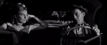 Movie still from “The Three Faces of Eve” (1957), directed by Nunnally Johnson – A man and a woman in a car looking at a cell phone; Medium shot, Low angle