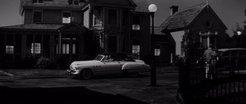 Movie still from “The Three Faces of Eve” (1957), directed by Nunnally Johnson – An old car parked on the side of the street; Extreme Wide shot, Low angle
